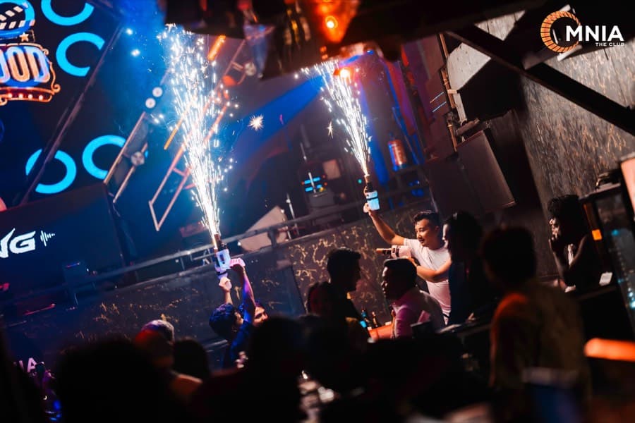 Bottle service arriving at a table — two sparkler fountains lit and raised on Bollywood night