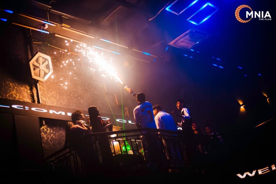 A sparkler fountain lit at the mezzanine rail, guests leaning over the balcony