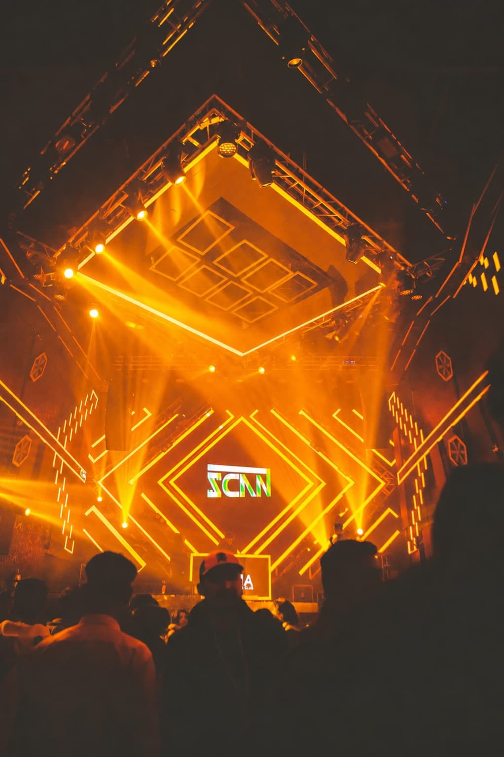 Amber beams thrown symmetrically across OMNIA's full lighting truss above a crowded floor