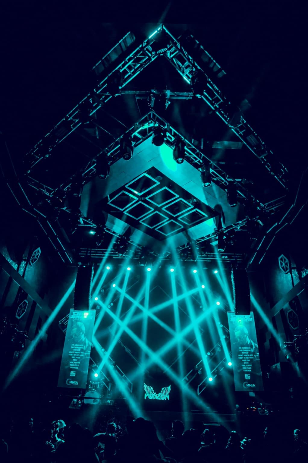 A fan of cyan beams thrown from the full lighting truss above OMNIA's stage